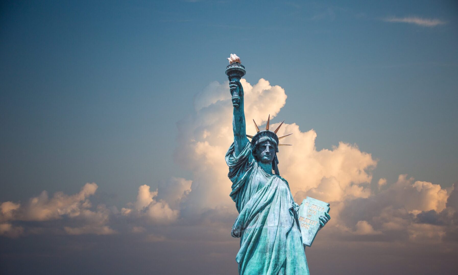 A statue of liberty with clouds in the background.